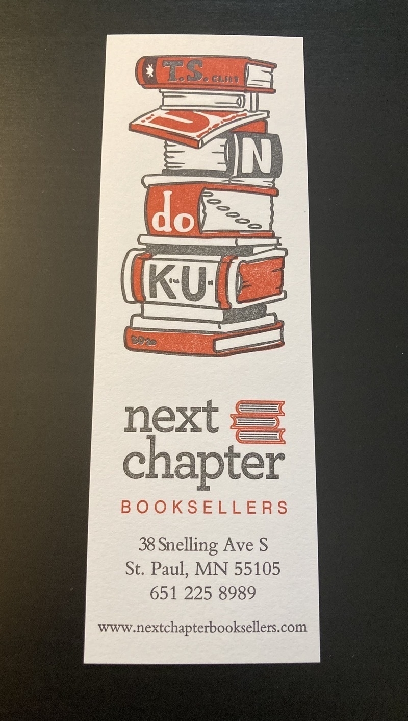 Bookmark with a drawing of a stack of books whose titles spell the word tsundoku