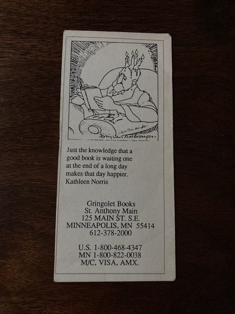 bookmark with a cartoon of a man reading by candles that are on the top of his bald head, wax slowly melting down his forehead