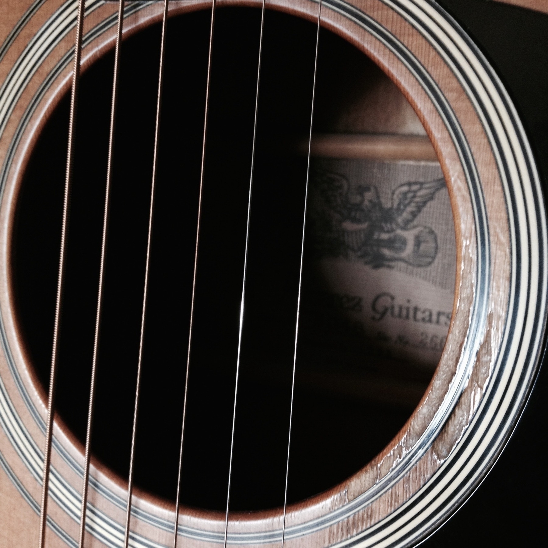 close-up on the sound hole of an Alvarez acoustic guitar, showing years of wear from strumming