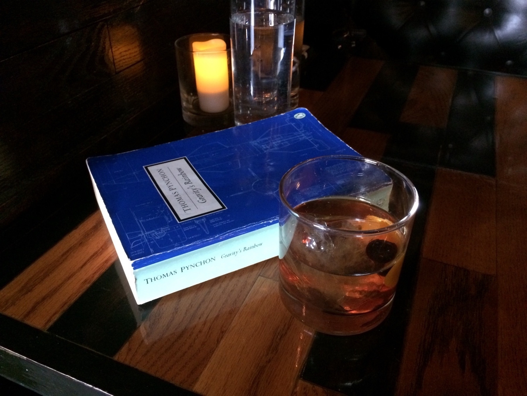 A copy of Gravity's Rainbow beside an Old Fashioned cocktail